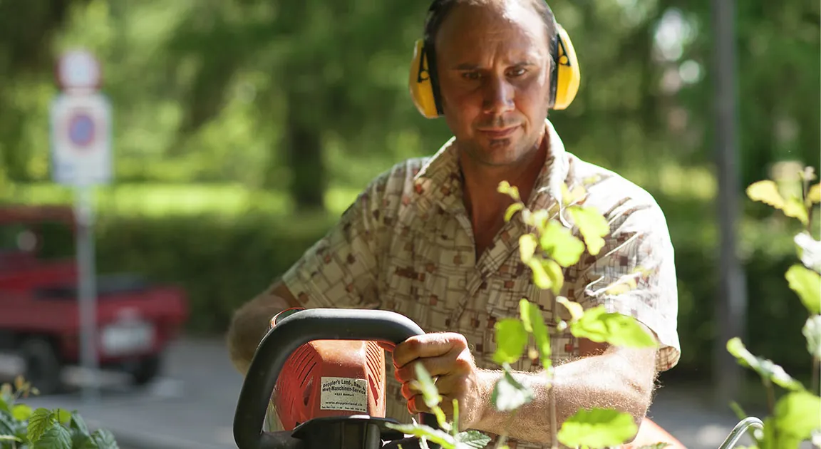 Gärtner mit Heckenschere und Gehörschutz