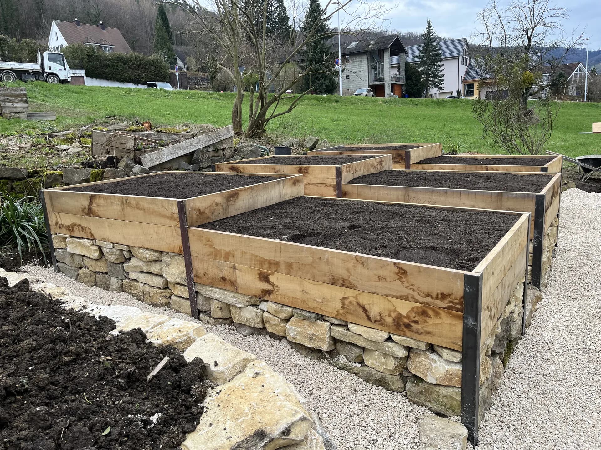 Holz-Hochbeet mit Natursteinmauer im Garten