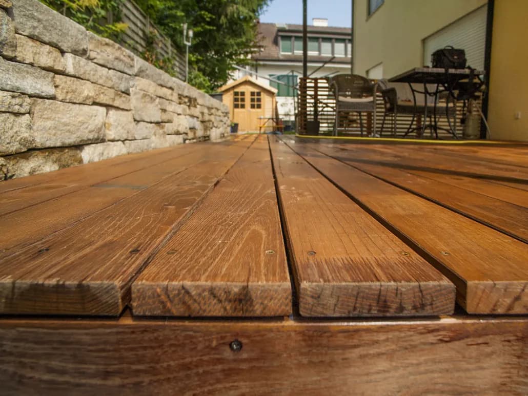 Holzterrasse mit Natursteinmauer und Gartenhaus