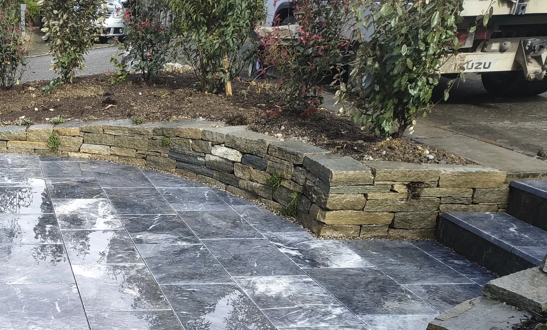 Vorplatz aus Granitplatten mit Natursteinmauer