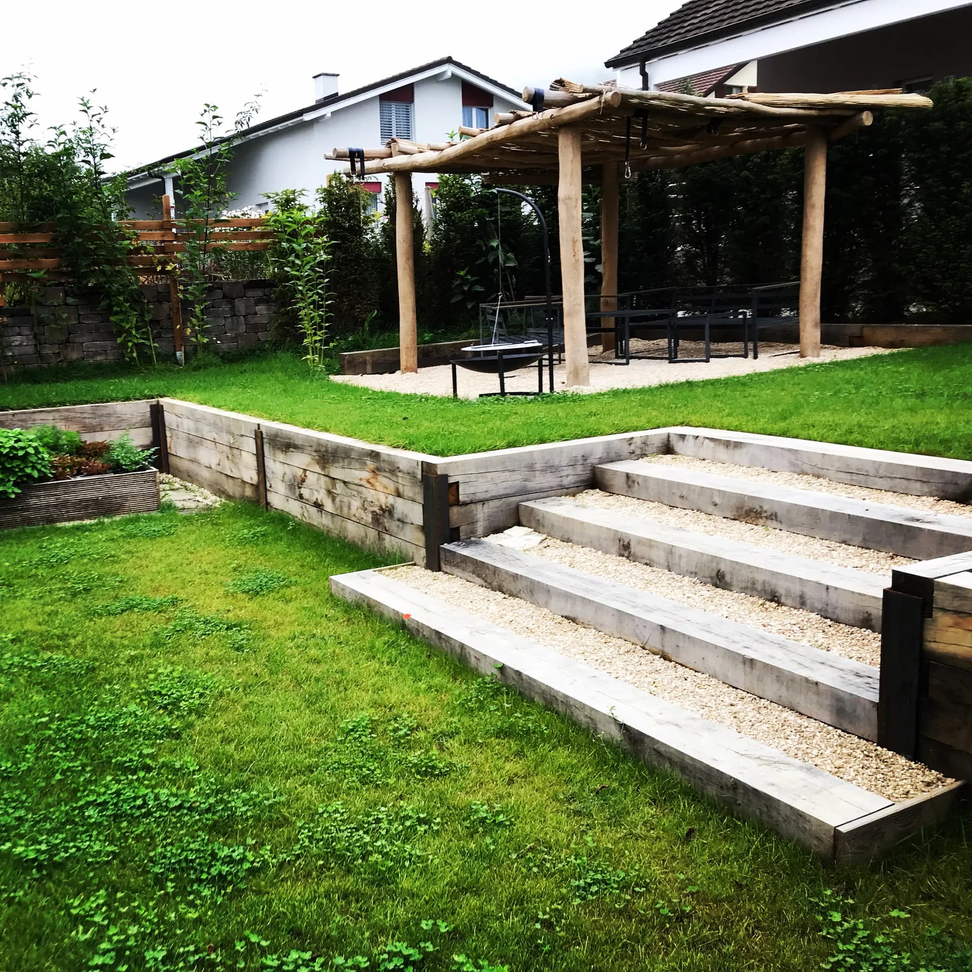 Kiesplatz mit Pergola und Holztreppe