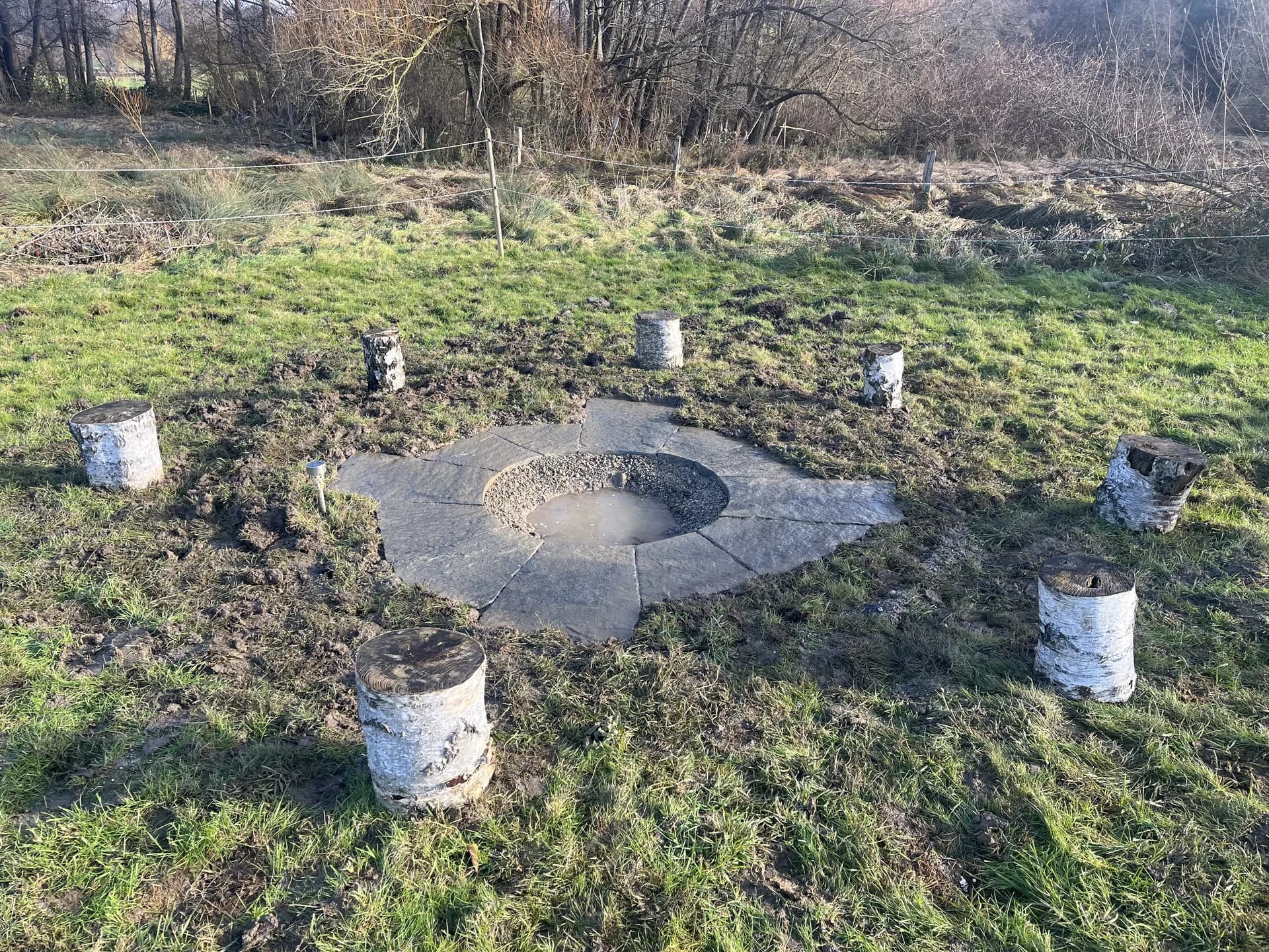 Feuerstelle aus Natursteinplatten mit Baumstämmen