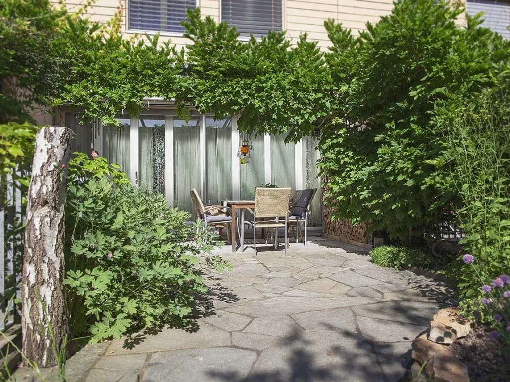 Sitzplatz aus Natursteinplatten unter Pergola